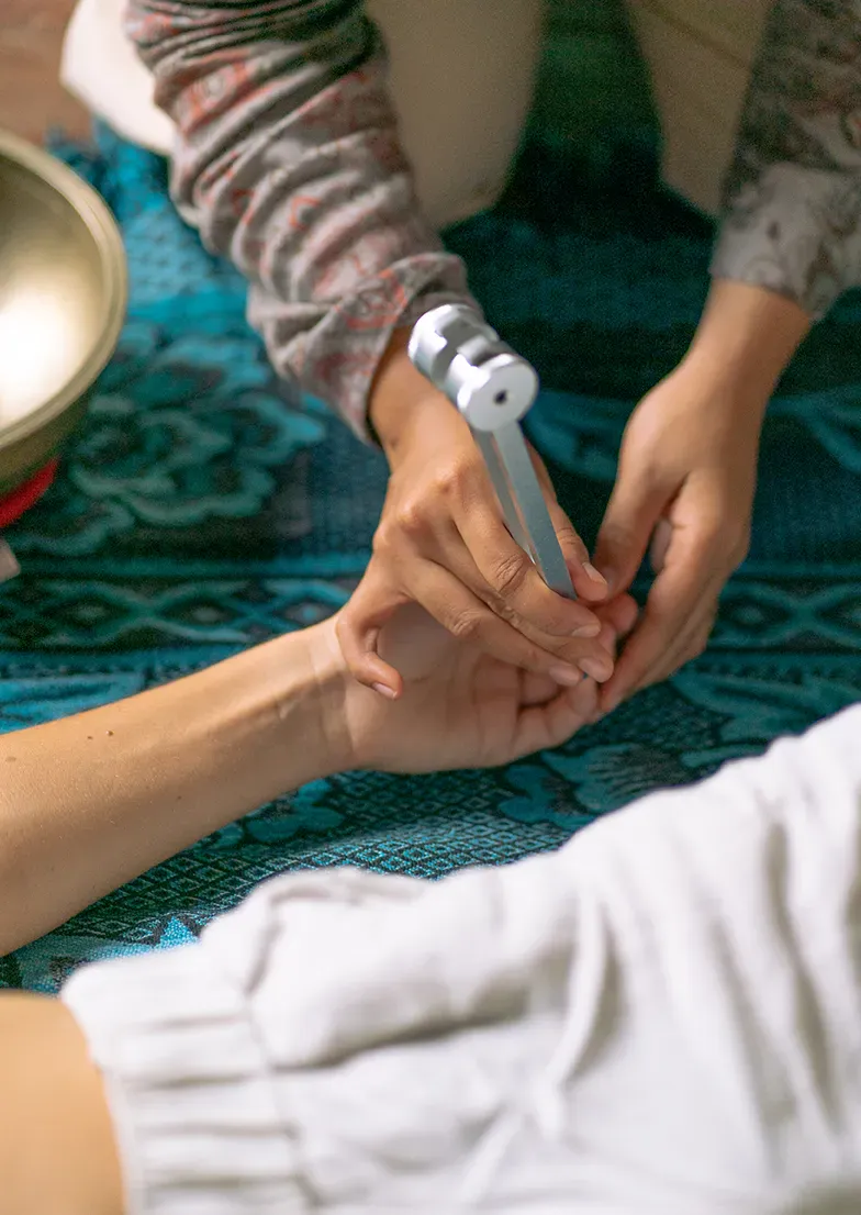 Person learning tuning fork technique on fingers at Ayutyas sound healing workshop